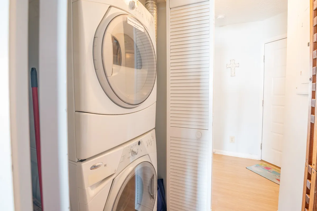 A closet with stacked washer and dryer units, white closet doors, and light-colored walls. The compact design highlights the convenience and practical amenities available for guests.