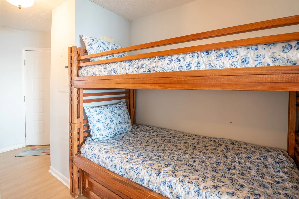 A custom-built bunk bed niche is visible, with floral bedding, a sturdy frame, and a doorway nearby. The space appears playful and inviting, perfect for children or additional guests looking for their own cozy sleeping spot.